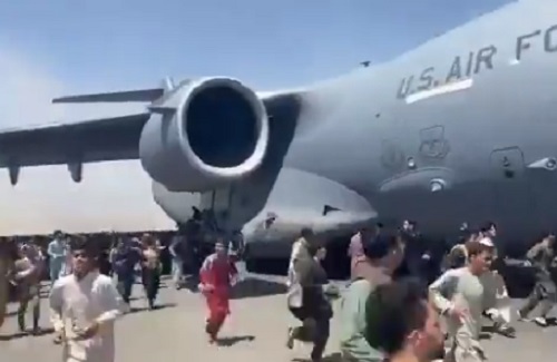 Afghans swarm a C-17 during takeoff from HKIA on Sunday, August 15, 2021.